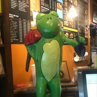 a statue of a frog holding a coffee mug