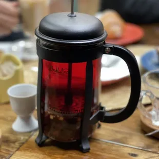 a red coffee pot with a spoon sticking out of it