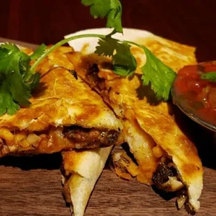 Jerkadilla is a Flour Tortilla filled with Cheddar Cheese Jerk Chicken Rice and Peas Drizzled w/Jerk BBQ sauce  and Mild Cilantro Salsa.