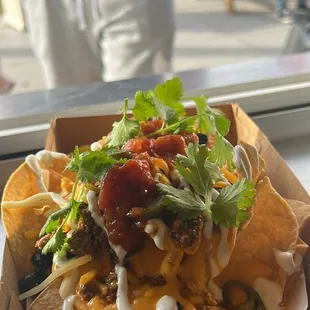 Loaded Nachos, seasoned angus ground beef, black beans, nacho + shredded cheese, salsa, sour cream, jalapeños, cilantro.