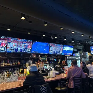 people sitting at a bar watching tvs
