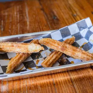 Crispy churro sticks, dusted with cinnamon sugar &amp; a drizzle of caramel sauce.