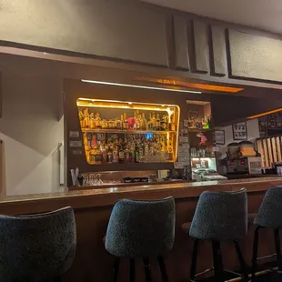 a row of bar stools in front of a bar
