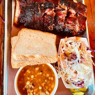 a tray of ribs, beans and coleslaw