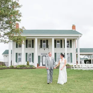 Couple beside their outdoor wedding ceremony spot on the front lawn