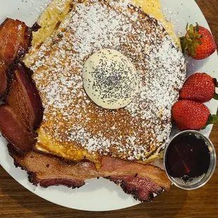 a plate of french toast with bacon and strawberries