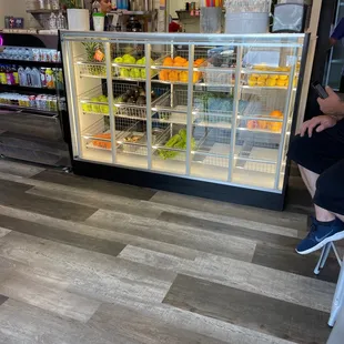 a man sitting in a chair in front of a refrigerated display case