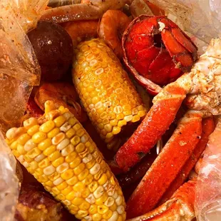 a pile of crab legs, corn on the cob, corn on the cob, and