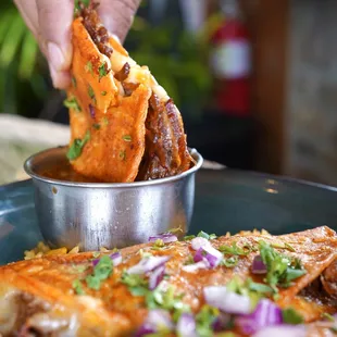 Quesabirria Tacos - three corn tortillas stuffed with mozzarella cheese and tender birria, topped with cilantro &amp; onions