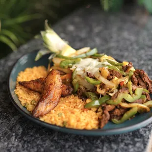 Crazy Pineapple - a halve pineapple loaded with steak, onions, bell peppers, grilled pineapple, and melted cheese, with rice.