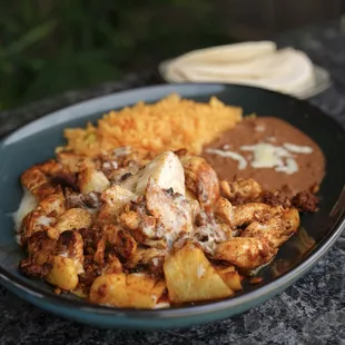 Chacalele - grilled chicken mixed with chorizo &amp; pineapple then drizzled in queso dip, accompanied by a side of rice, beans &amp; warm tortillas