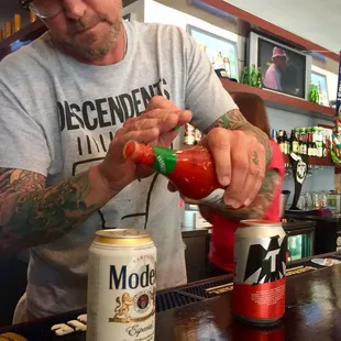 a man pouring ketchup into a can