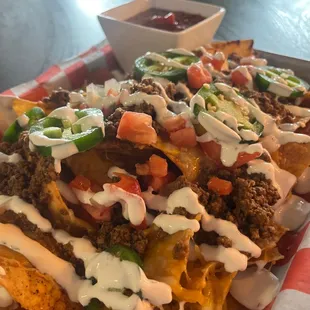 a tray of nachos with sauce and toppings
