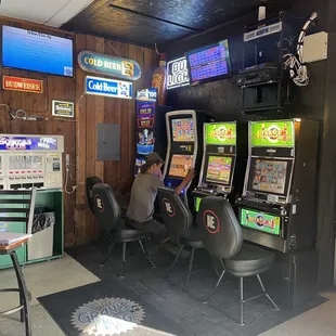 a man sitting in a chair in front of a row of slot machines
