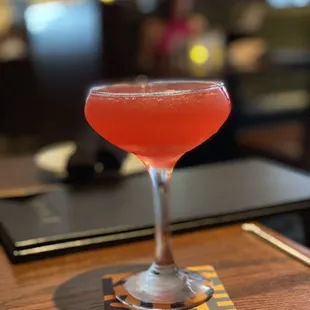 a red cocktail in a coupe glass