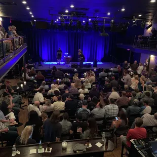 a large crowd of people sitting in front of a stage