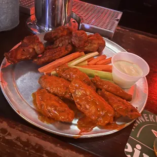 a plate of wings, carrots and celery