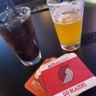 a glass of beer and two coasters