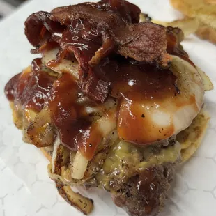 The &quot;backyard burger&quot; in house ground beef pattie topped with crispy hickory bacon, grilled onions and cheese on a toasted bun.