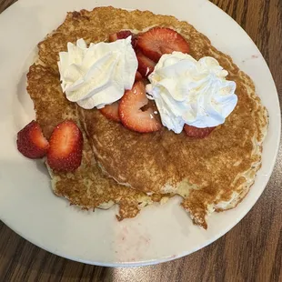 a plate of pancakes with whipped cream and strawberries