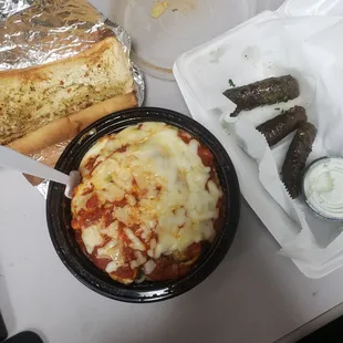 Chicken parmesan pasta, garlic bread, olive leaves with tzaziki sauce.
