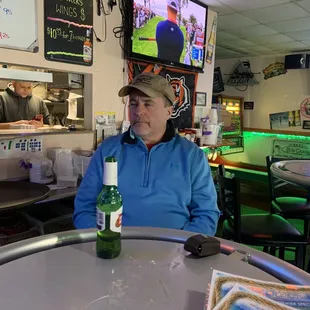 a man sitting at a table with a bottle of beer