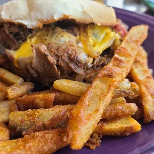 a beef sandwich and fries on a purple plate