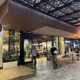 two people walking in front of a coffee shop