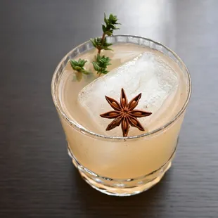 a glass of a drink with a star anise garnish