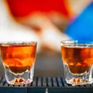 two shot glasses of alcohol on a bar