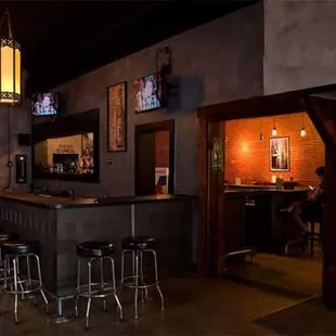 a bar with stools and televisions