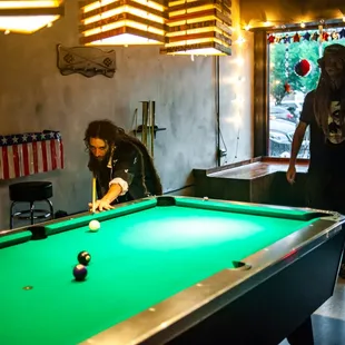 two men playing pool in a bar