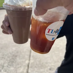 a person holding two cups of iced coffee