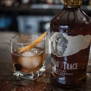 a glass of whiskey next to a bottle