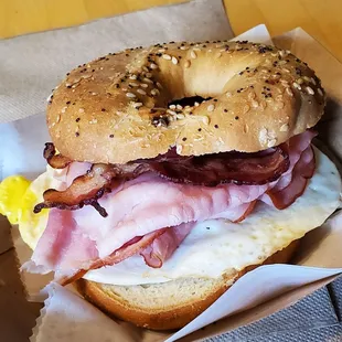 Breakfast sandwich with egg, ham, bacon on everything bagel.