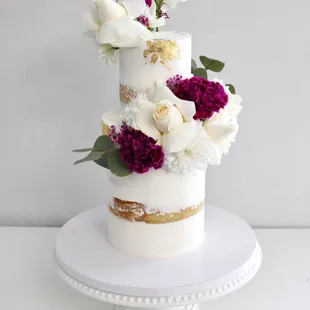 a three tiered cake with white and purple flowers