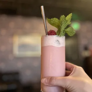 a hand holding a glass of a drink