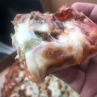 a hand holding a slice of pizza
