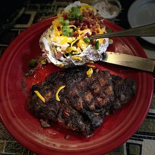 a steak and potatoes on a red plate