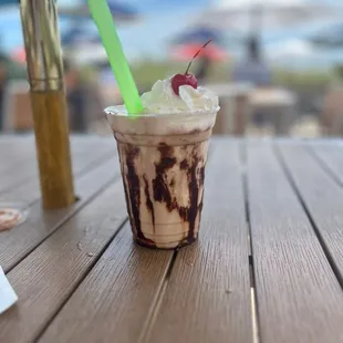 a cup of ice cream with a straw and a cherry on top