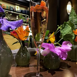 a glass of champagne and vases of flowers