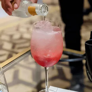 a person pouring a drink into a glass