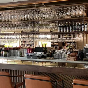 a bar with wine glasses on the shelves