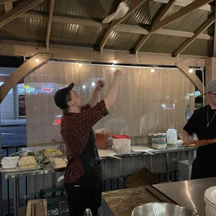 The guys outside cooking pizza or fabulous, making delicious pizza