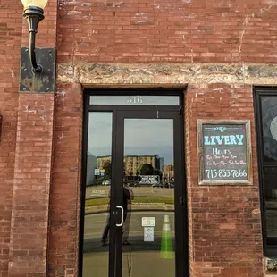 The front door and posted hours of The Livery