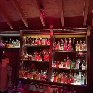 a man standing in front of a wall of liquor bottles