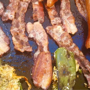 bacon and hot dogs cooking on a grill