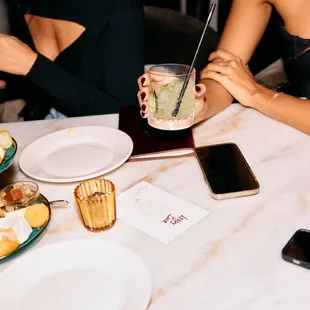a woman sitting at a table holding a drink