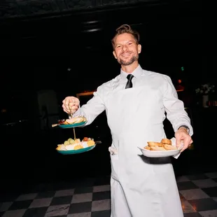 a waiter holding two plates of food