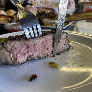 a piece of steak on a plate with a knife and fork